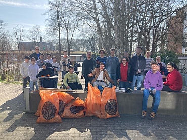 Die Schülerinnen und Schüler lächeln in die Kamera. Vor ihnen stehen volle Säcke Müll, die sie gesammelt haben. 