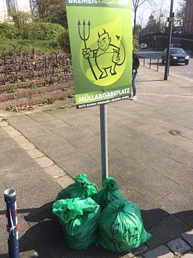 gesammelter Müll unter dem Schild mit dem Logo 